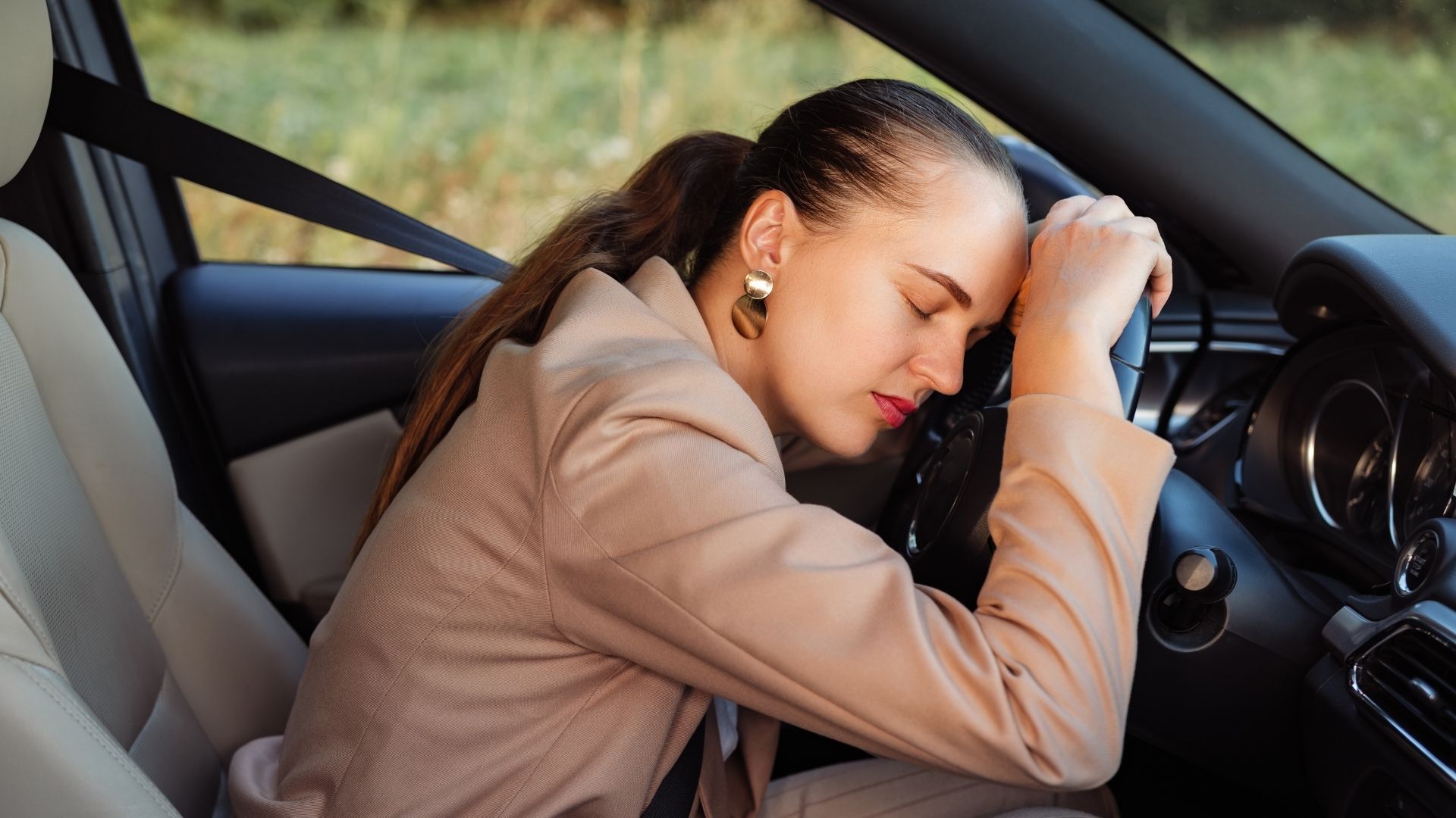 Una mujer dormida encima del volante mostrando cansancio.