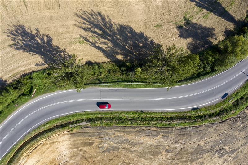Imagen de un coche rojo en una carretera interurbana
