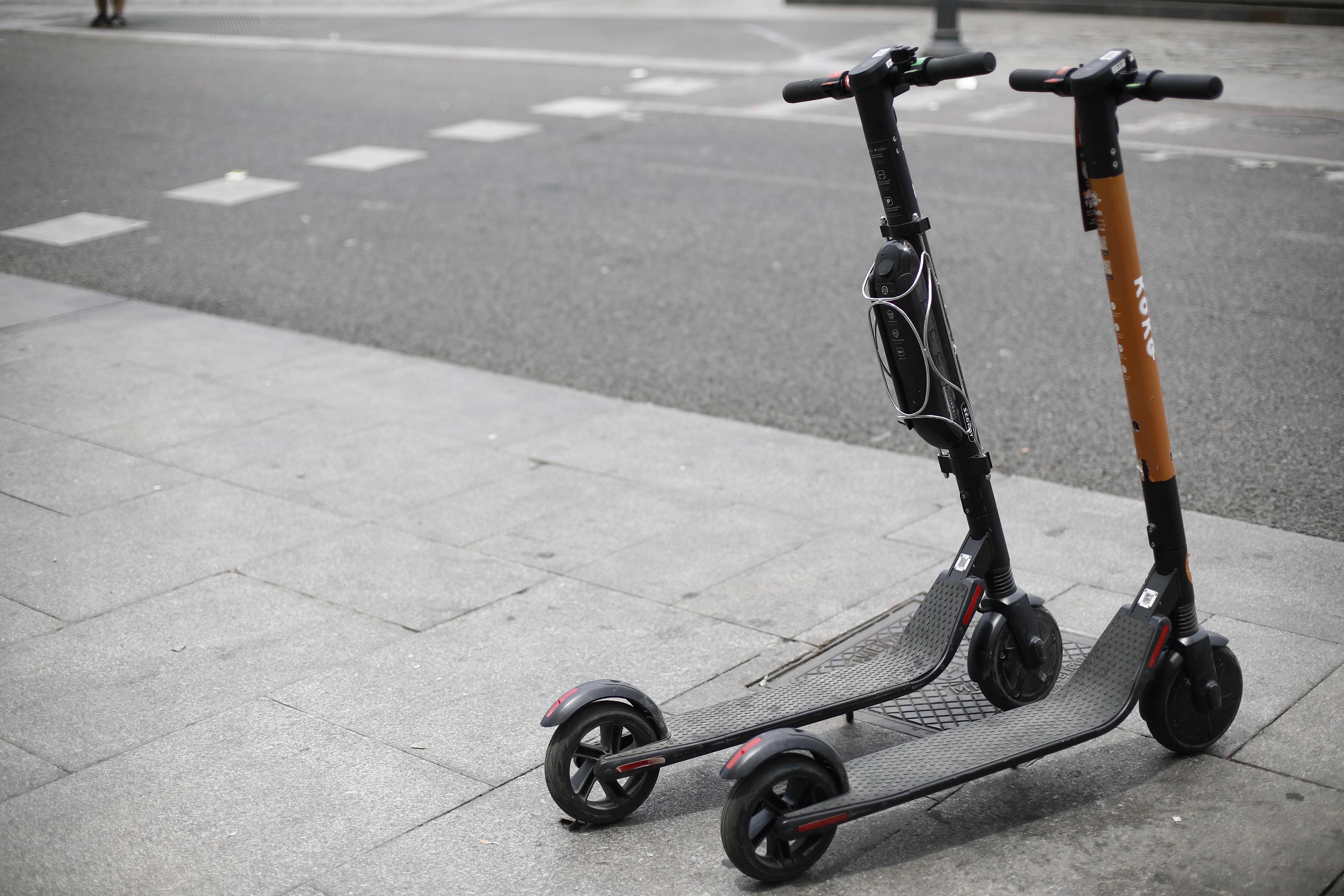 Dos patinetes eléctricos aparcados en la acera. 